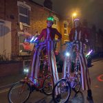 glow jugglers on stilt bikes